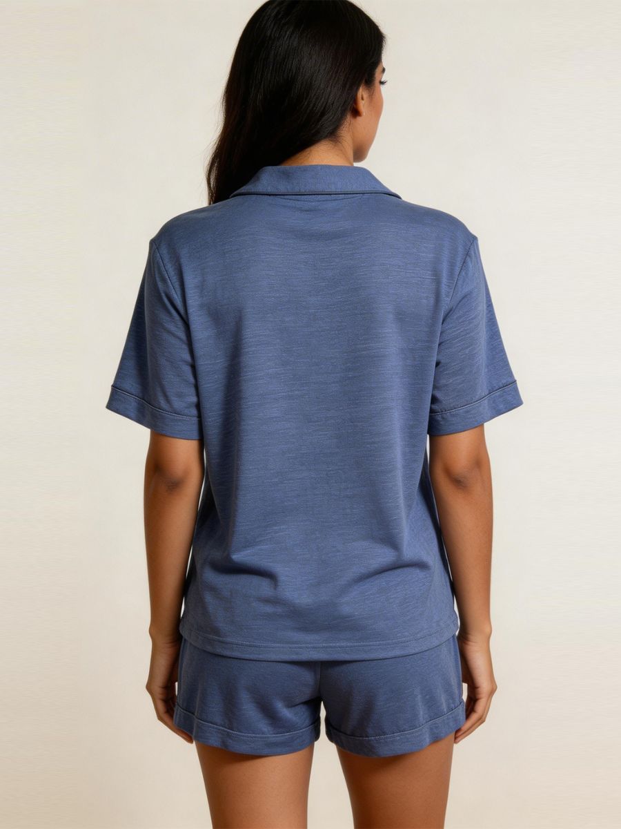 Person wearing a blue polo shirt and shorts set on a beige background