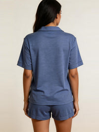 Person wearing a blue polo shirt and shorts set on a beige background