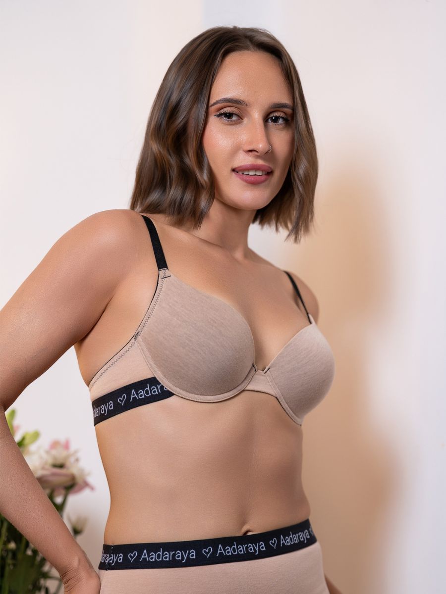 Woman wearing a beige bra with 'Aadaraya' branding on a neutral background