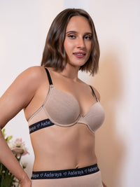 Woman wearing a beige bra with 'Aadaraya' branding on a neutral background