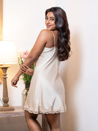 Woman wearing a white nightgown in a softly lit room.