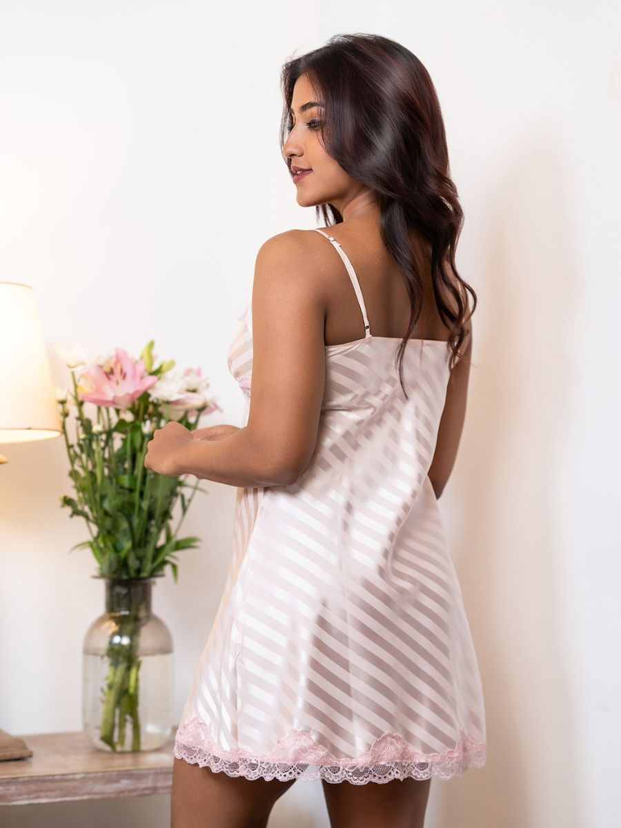 Woman wearing a white lace nightgown holding flowers indoors.