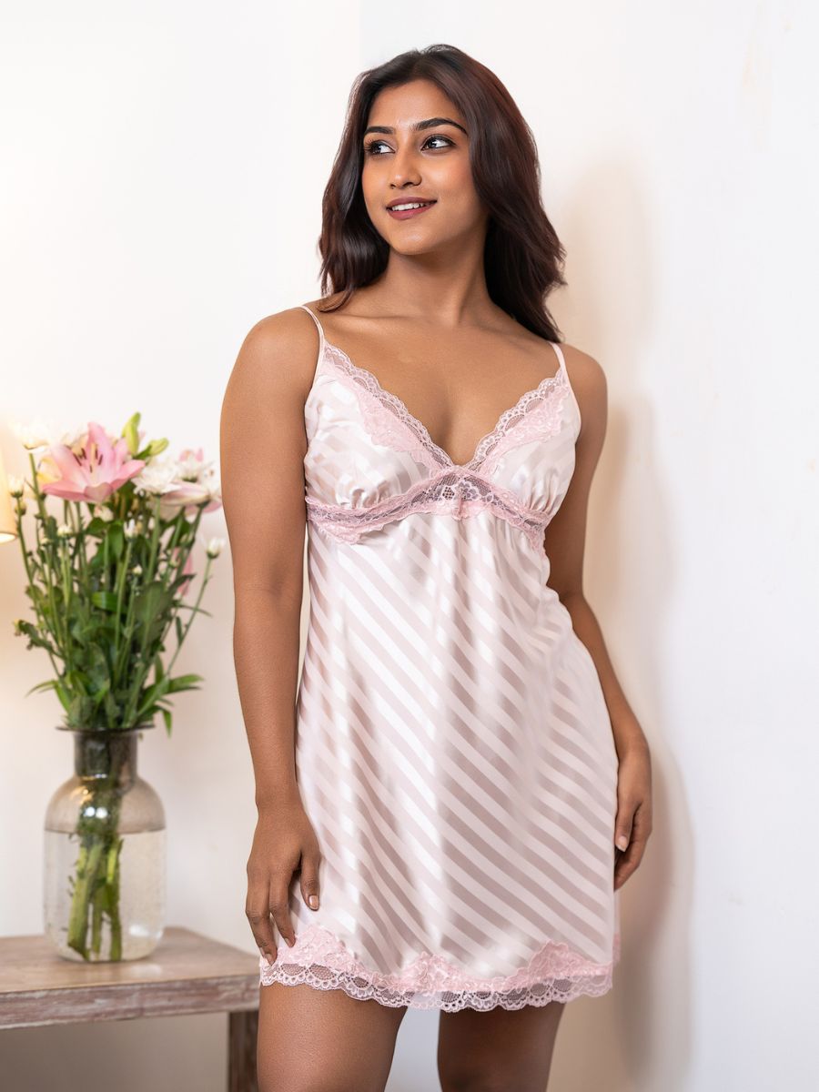 Woman wearing a pink lace nightgown with a vase of flowers in the background