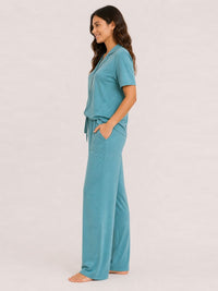 Woman wearing a teal pajama set on a white background