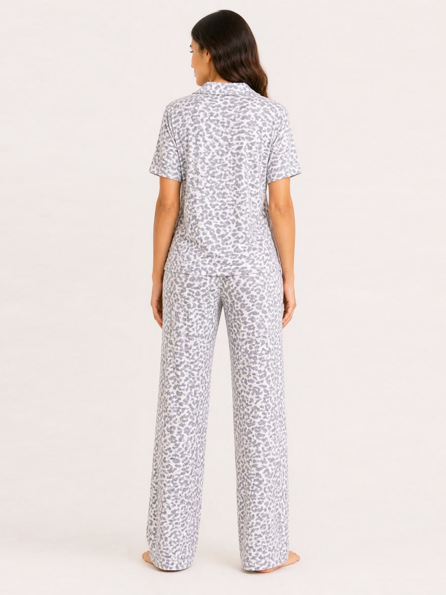 Woman wearing a white pajama set with black pattern on a light pink background