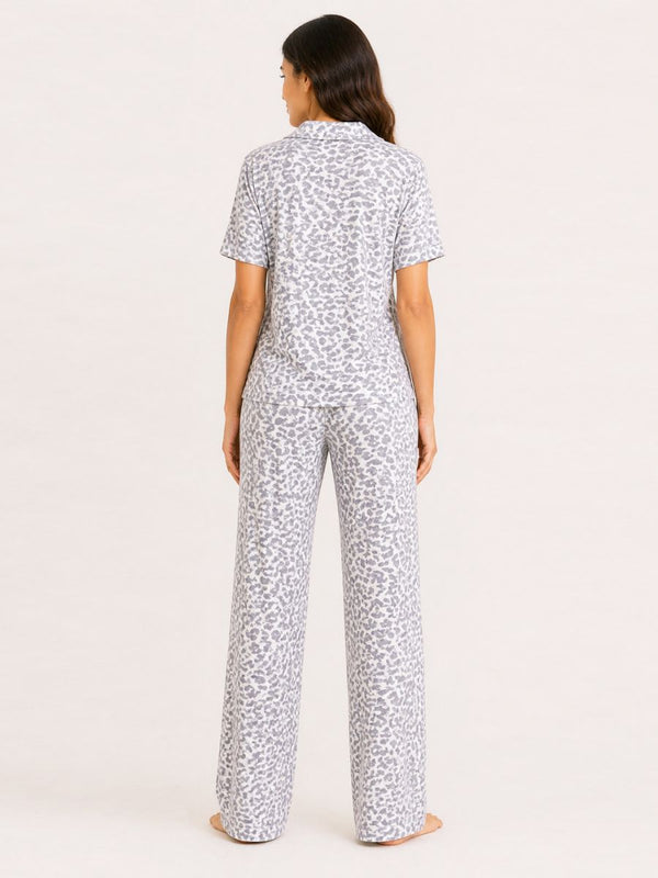 Woman wearing a white pajama set with black pattern on a light pink background
