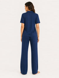 Woman wearing a navy blue pajama set on a white background