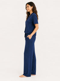 Woman wearing a navy blue pajama set on a white background
