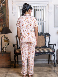 Person wearing a floral pajama set in a room with a lamp and chair.