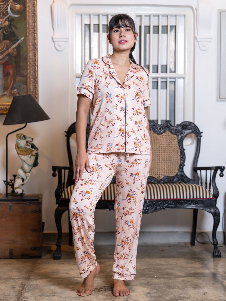 Woman wearing a floral pajama set in a room with a chair and lamp.