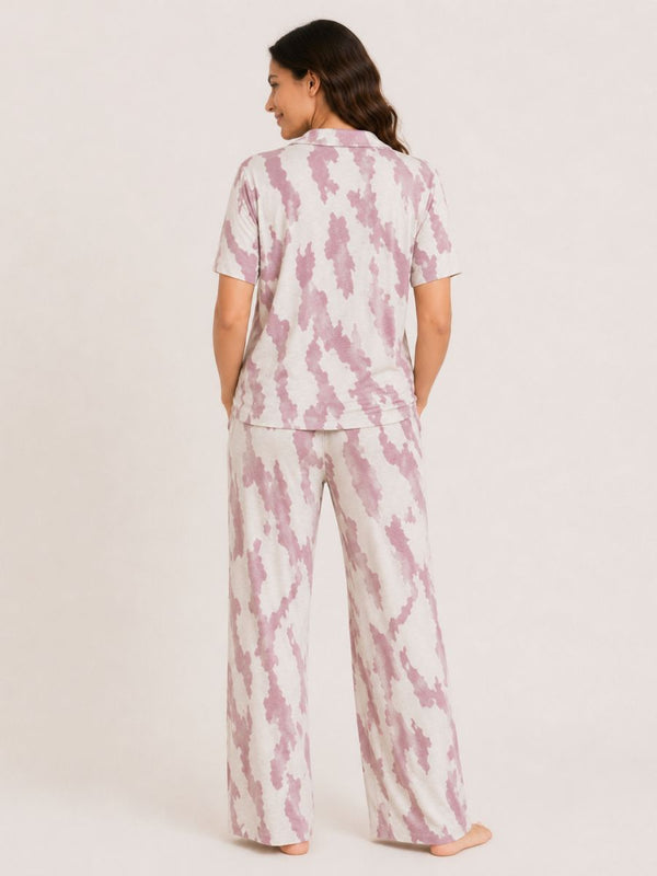 Woman wearing a pink and white tie-dye pajama set on a plain background