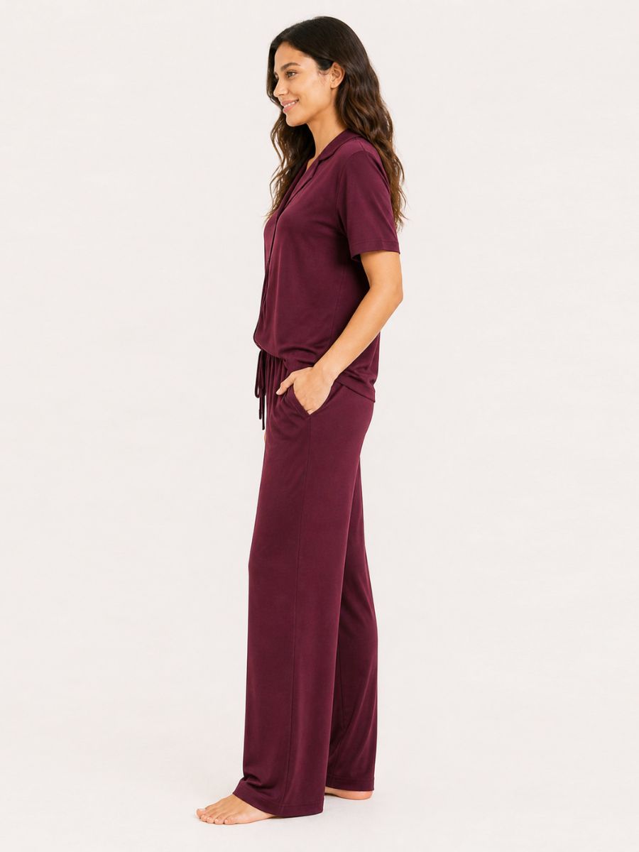 Woman wearing a burgundy pajama set on a white background