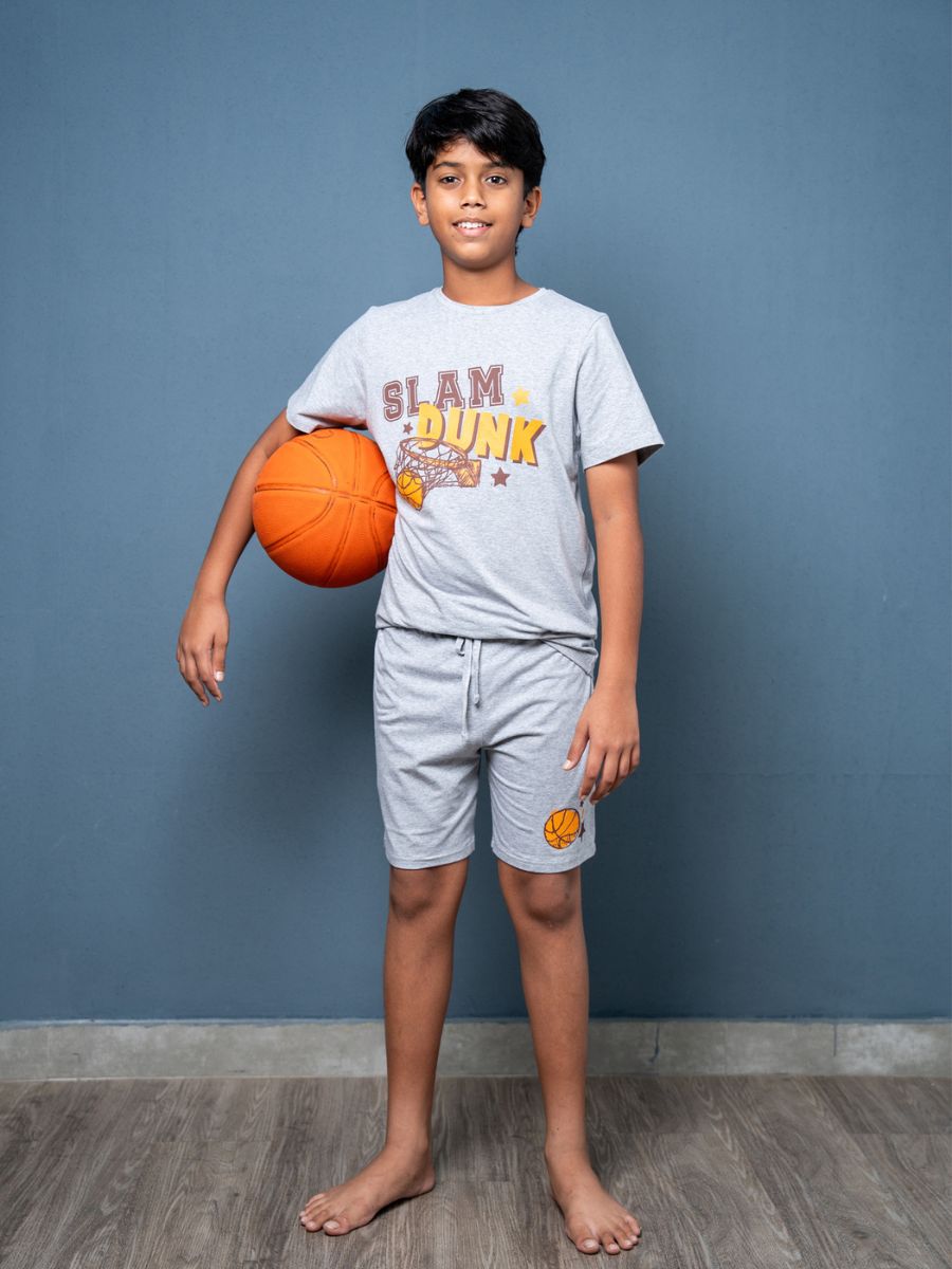 Child holding a basketball wearing a 'Slam Dunk' t-shirt against a blue wall.