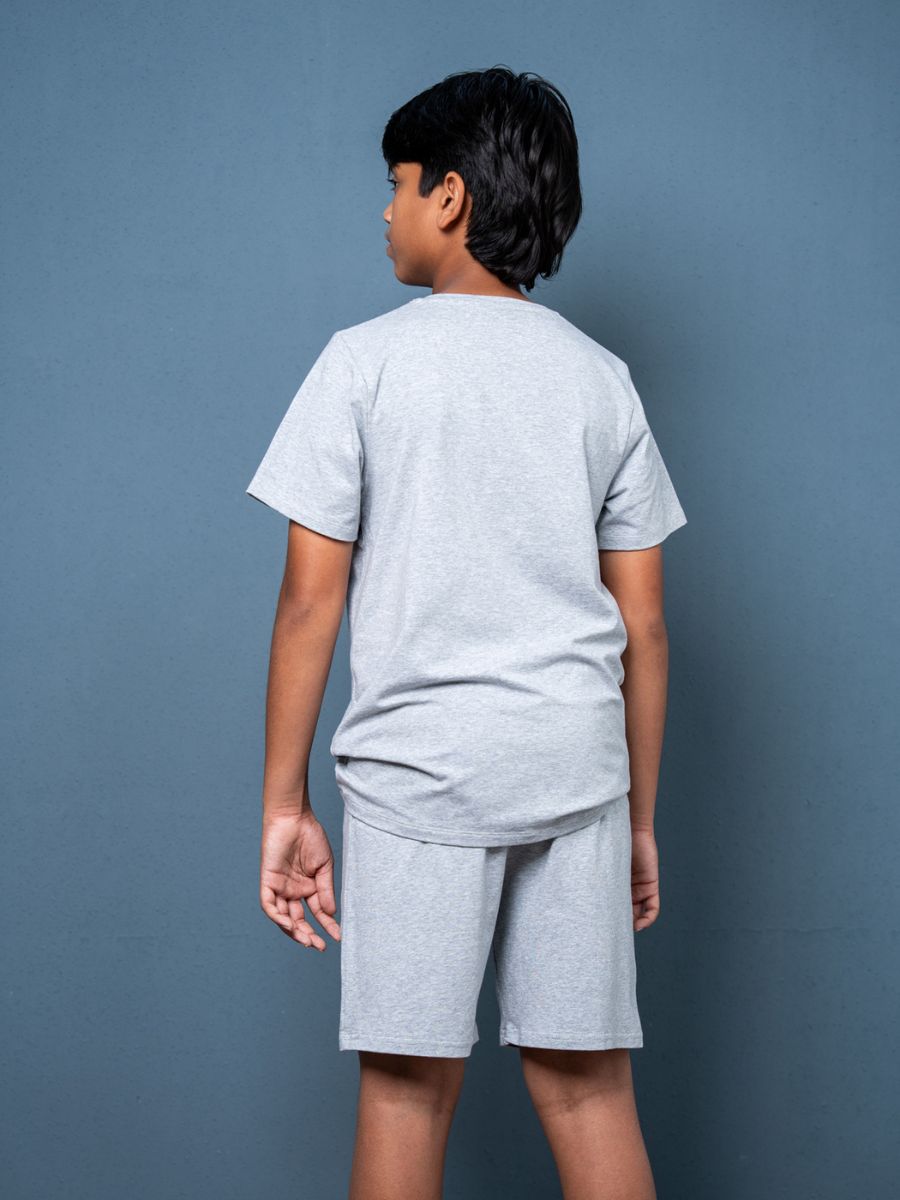 Child wearing a gray t-shirt and shorts set against a blue background