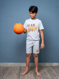 Child holding an orange basketball wearing a 'Slam Dunk' t-shirt against a blue wall.