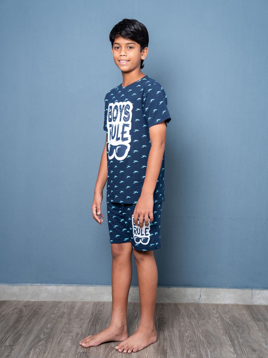 Child wearing a navy blue pajama set with 'Boys Rule' text against a gray background