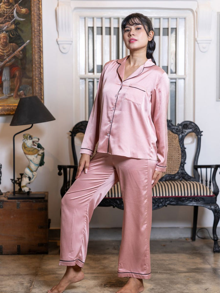 Woman wearing pink satin pajamas standing in a room with vintage decor.