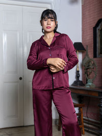 Woman wearing a burgundy pajama set in a room with a white door and lamp.