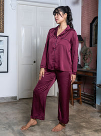 Woman wearing a burgundy pajama set in a room with a white door and wooden furniture.