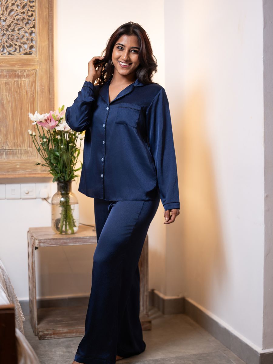 Woman wearing a navy blue pajama set in a bedroom setting.