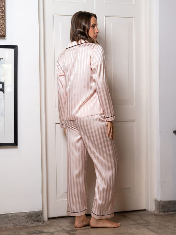 Woman wearing pink striped pajamas standing in a room with a white door.