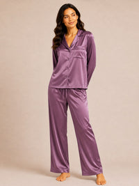 Woman wearing a purple satin pajama set against a beige background