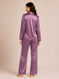 Person wearing a purple satin pajama set on a beige background