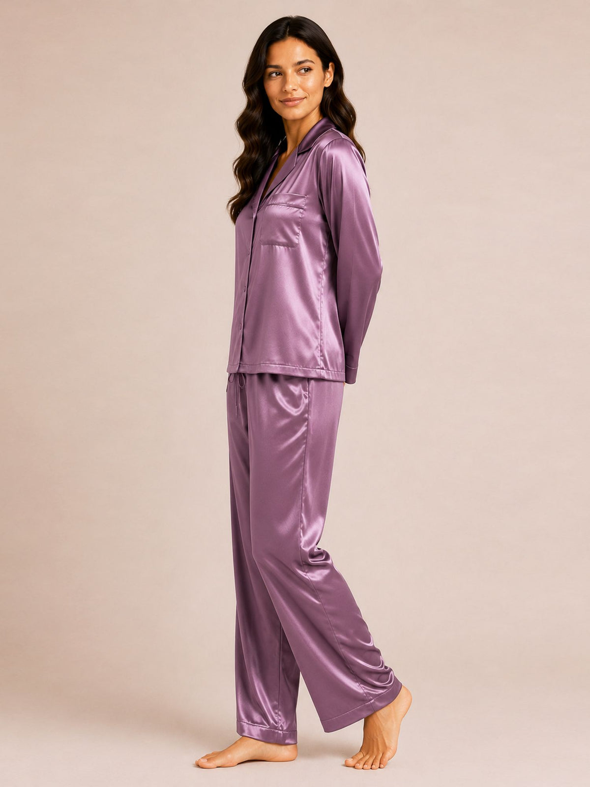 Woman wearing a purple satin pajama set on a beige background