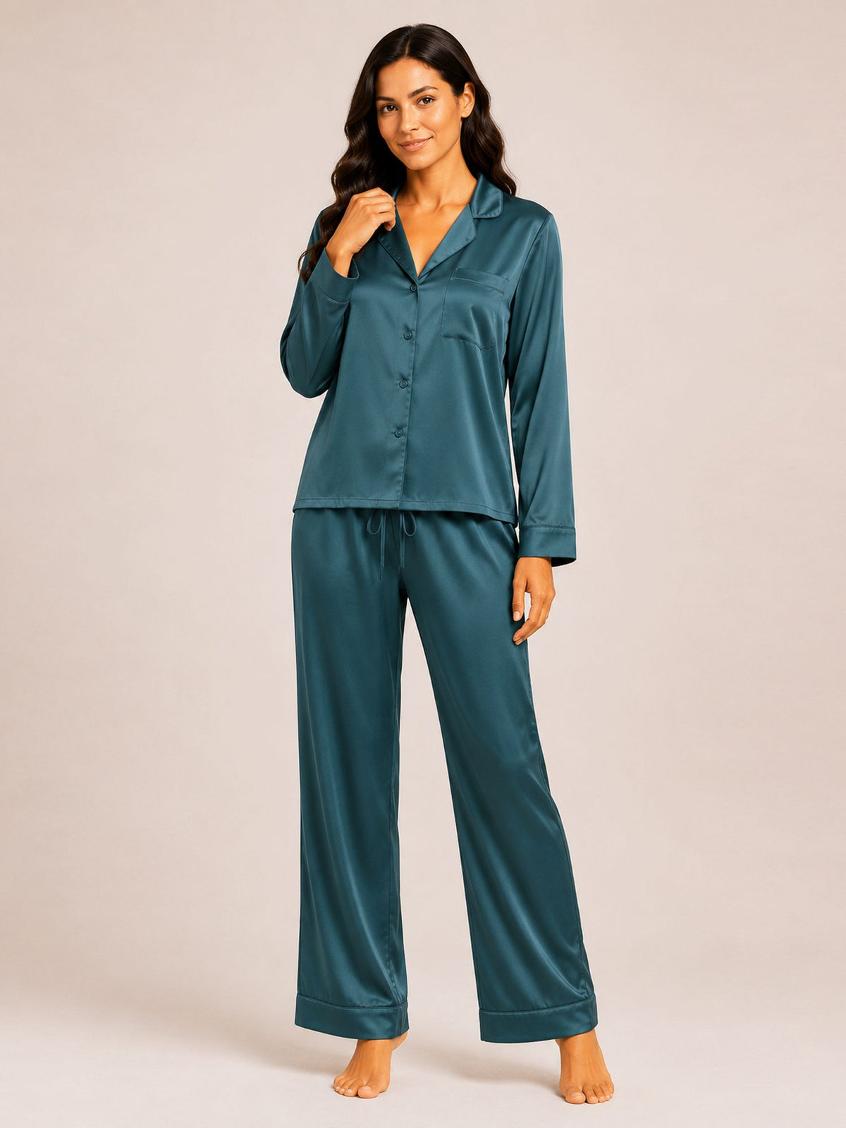 Woman wearing teal satin pajamas on a plain background