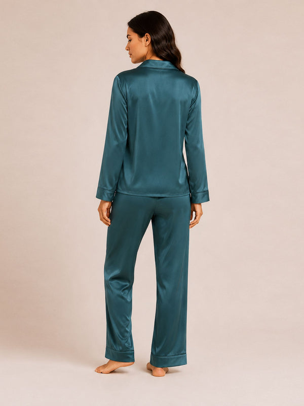 Woman wearing teal satin pajamas on a beige background