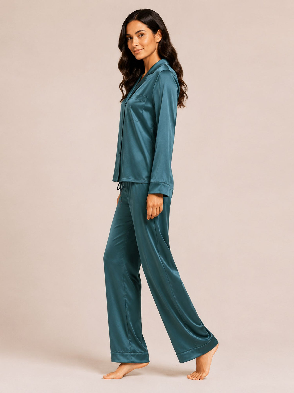 Woman wearing teal satin pajamas on a beige background