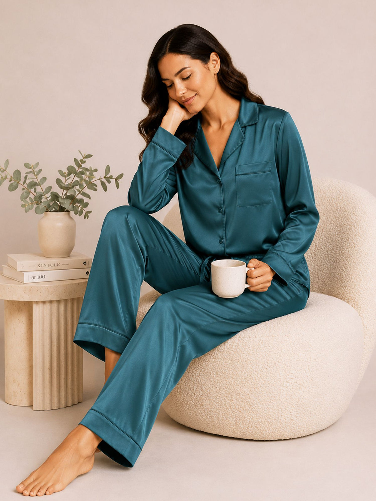 Woman in teal pajamas sitting on a white chair holding a mug.