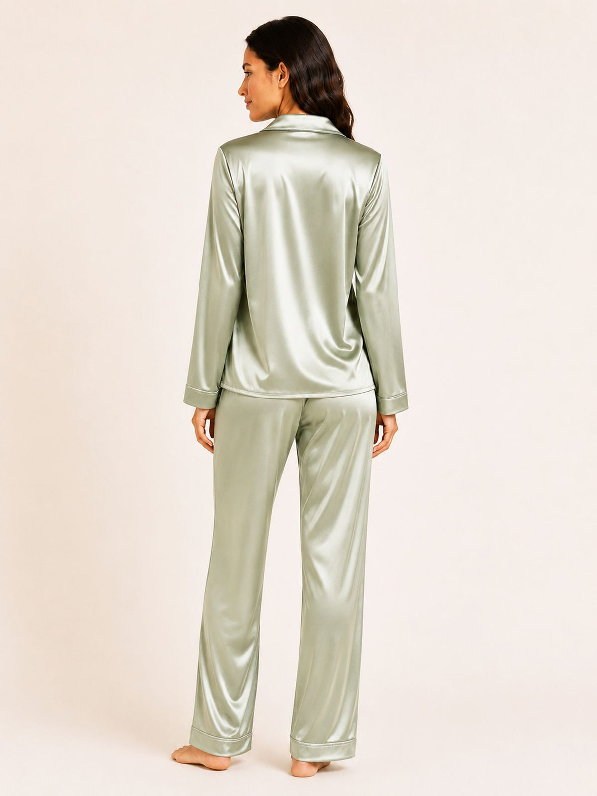 Person wearing a green satin pajama set on a plain background