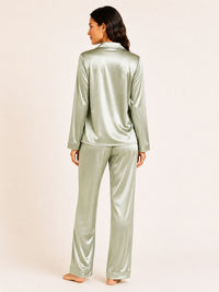 Person wearing a green satin pajama set on a plain background