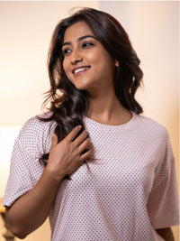 Woman wearing a light pink top with black polka dots against a neutral background