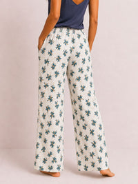 Person wearing floral-patterned pants on a plain background