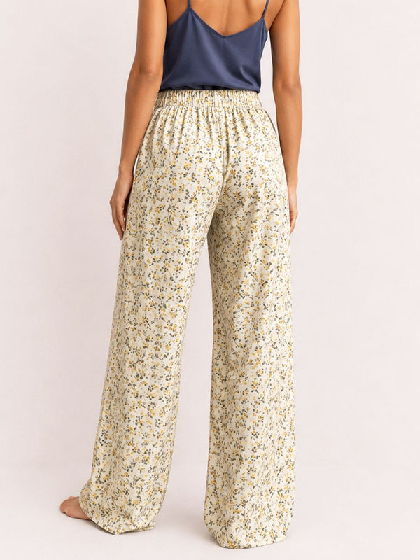 Woman wearing floral wide-leg pants and a dark top on a light background
