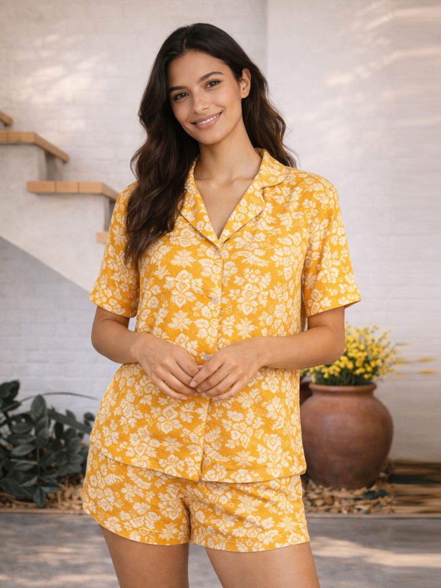 Woman wearing a yellow floral pajama set standing in a home setting.