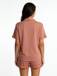 Woman wearing a pink polo shirt and shorts set on a white background