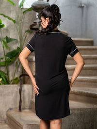 Woman wearing a black dress with white trim standing on stone steps.