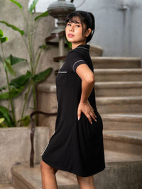 Woman in a black dress standing outdoors with plants and steps in the background