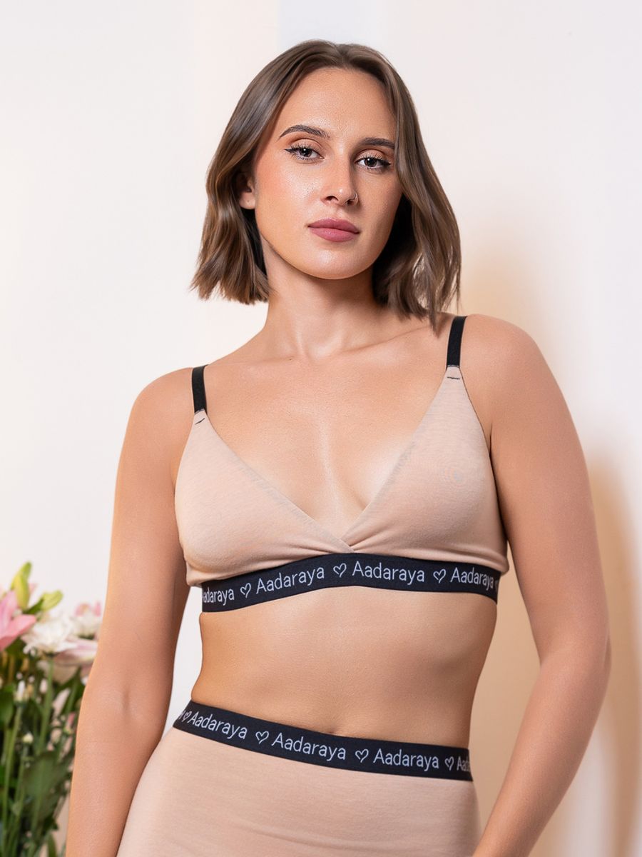 Woman wearing a beige bra with 'Aadaraya' branding against a light background