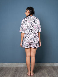 Person wearing a patterned pajama set against a blue wall.
