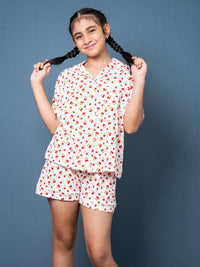 Young girl wearing a white pajama set with red floral pattern against a blue background