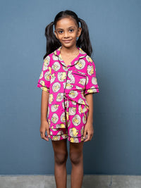 Young girl wearing a pink pajama set with cartoon characters against a blue background