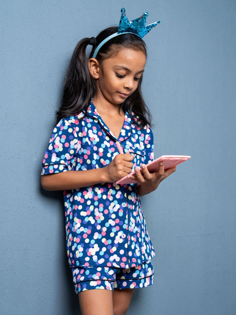 Young girl in a blue floral outfit with a pink tablet against a gray background