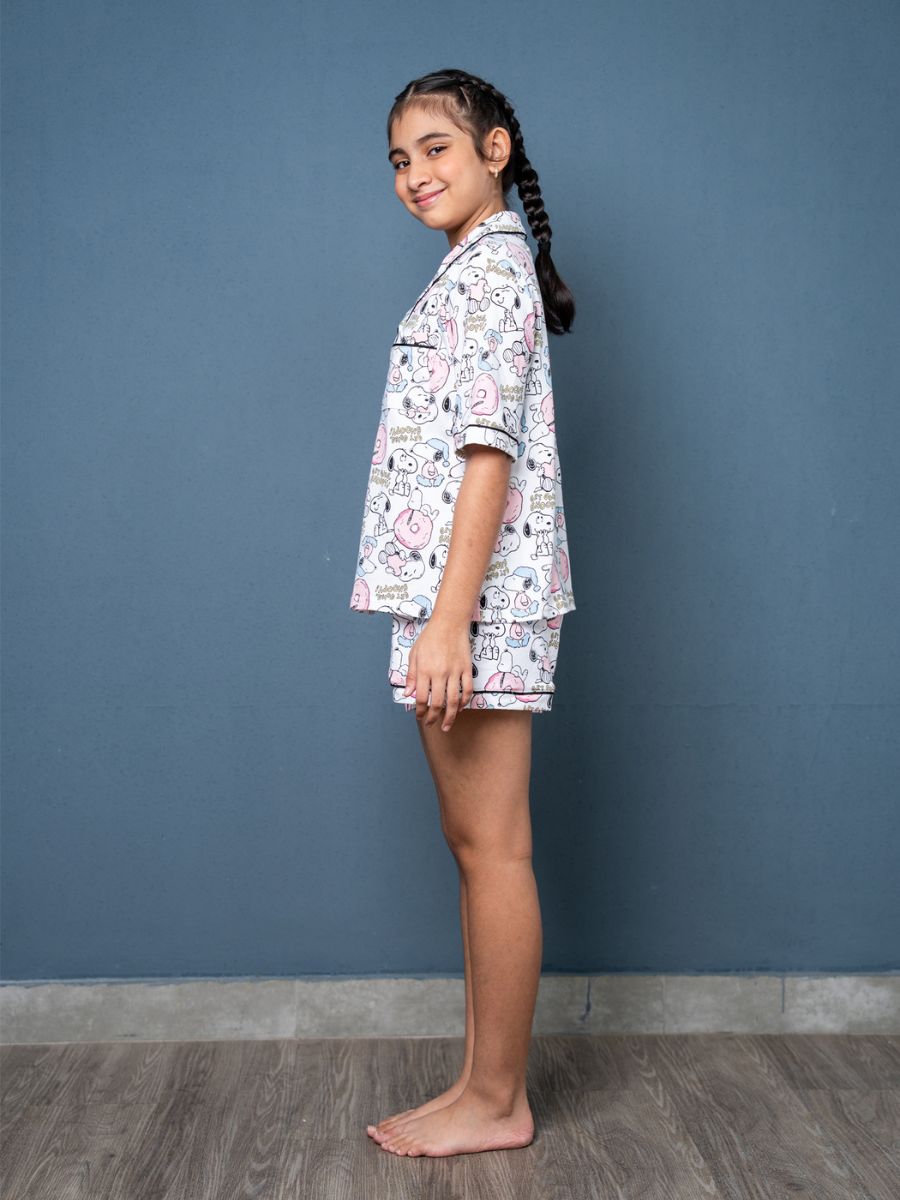 Young girl wearing a patterned pajama set against a blue wall.