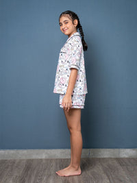 Young girl wearing a patterned pajama set against a blue wall.