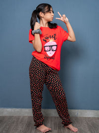 Person wearing a red shirt with a graphic design and black pants with red patterns against a blue wall.
