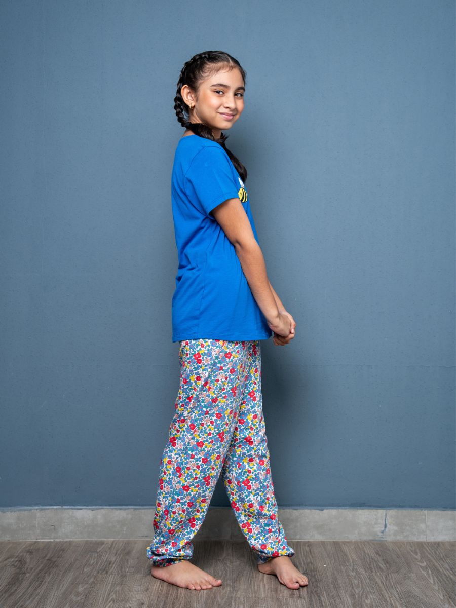Person wearing a blue shirt and colorful patterned pants against a gray background